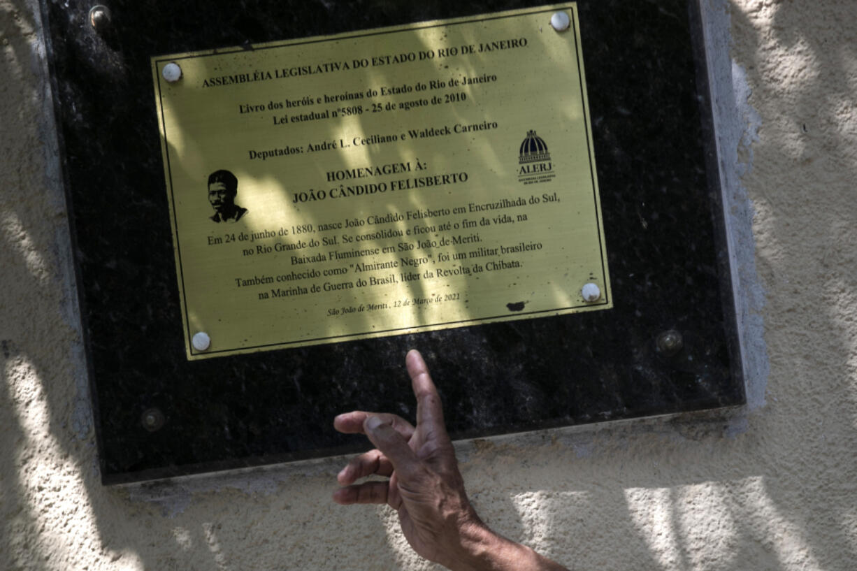 Adalberto C&acirc;ndido points to a memorial plaque honoring his father Jo&atilde;o C&acirc;ndido, a black sailor who led a revolt against against regular whipping by the Brazilian naval officers in 1910, in Sao Joao de Meriti, Rio de Janeiro state, Brazil, Thursday, Dec. 21, 2023. Kicked out of the navy, he and his family are seeking compensation for the pension benefits and promotions he and his family missed out on.