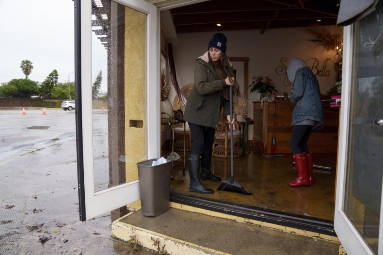 People push out water from a flooded business, Thursday, Feb. 1, 2024 in Seal Beach, Calif. Heavy rain flooded roadways and much-needed snow piled up in the mountains on Thursday as the first of back-to-back atmospheric rivers pummeled California.