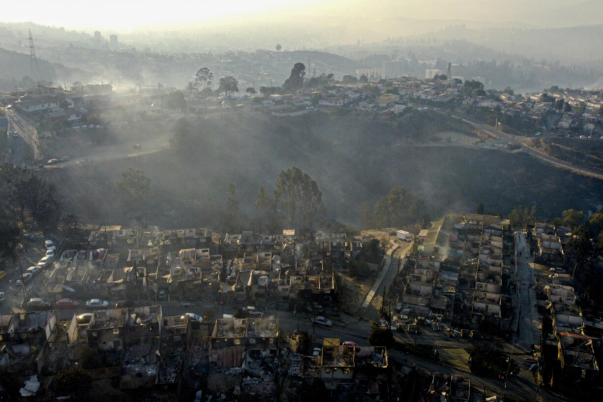 Smoke raises from  burnt-out houses after a forest fire reached Villa Independencia neighborhood in Vina del Mar, Chile, Saturday, Feb. 3, 2024.