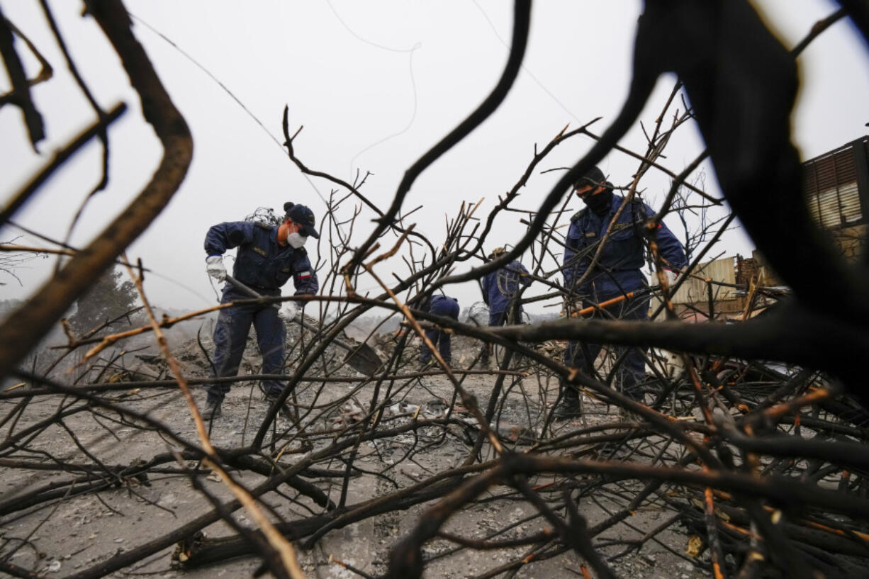 Chilean Navy members clean up burnt areas of the Villa Independencia neighborhood that was affected by forest fires in Vina del Mar, Chile, Tuesday, Feb. 6, 2024.