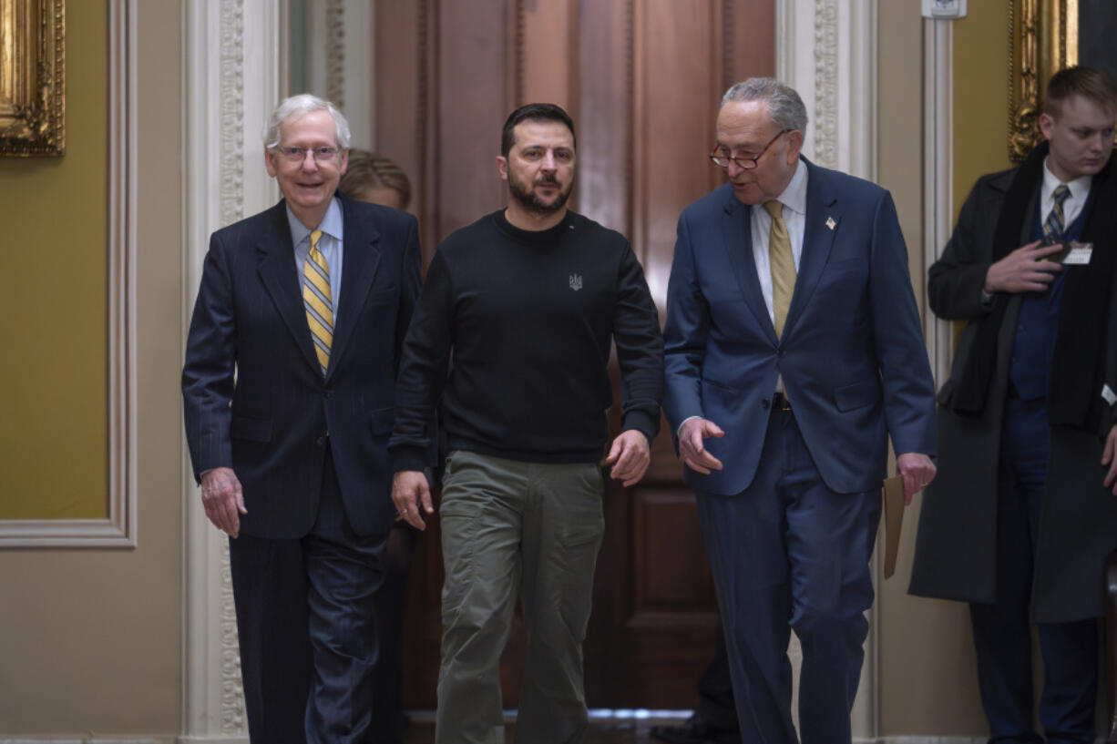 FILE - Ukrainian President Volodymyr Zelenskyy, center, is escorted by Senate Minority Leader Mitch McConnell, R-Ky., left, and Senate Majority Leader Chuck Schumer, D-N.Y., as he comes to the Capitol in Washington to issue a plea for Congress to break its deadlock and approve continued wartime funding for Ukraine, Dec. 12, 2023. Two months later, that aid request had still not been met but Schumer and McConnell are keeping the Senate in session on Super Bowl weekend to force funding for Ukraine and Israel. (AP Photo/J.
