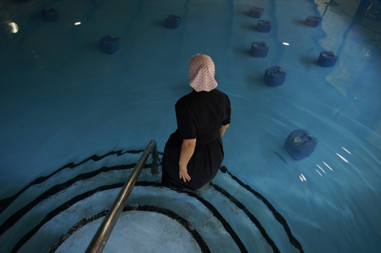 An Amish woman from Ohio wades into a pool with BioHealing generator canisters at Tesla Wellness Hotel and MedBed Center on Wednesday, Nov. 15, 2023, in Butler, Pa. The company claims the canisters exude &ldquo;life force energy,&rdquo; or biophotons. Testimonials from the company&rsquo;s patients speak to the device&rsquo;s power to treat cancer, dementia, chronic pain, and even broken bones.