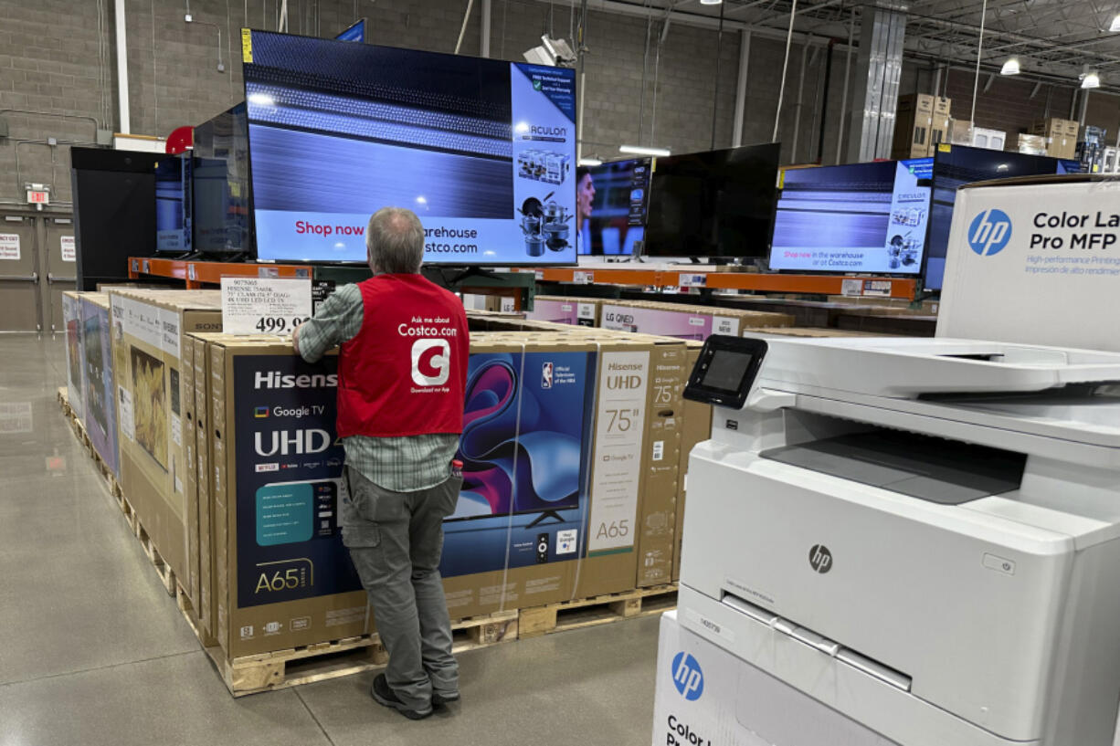 An associate checks over a big-screen television on display in a Costco warehouse Tuesday, Feb. 6, 2024, in Colorado Springs, Colo. On Tuesday, The Labor Department issues its report on inflation at the consumer level in January.