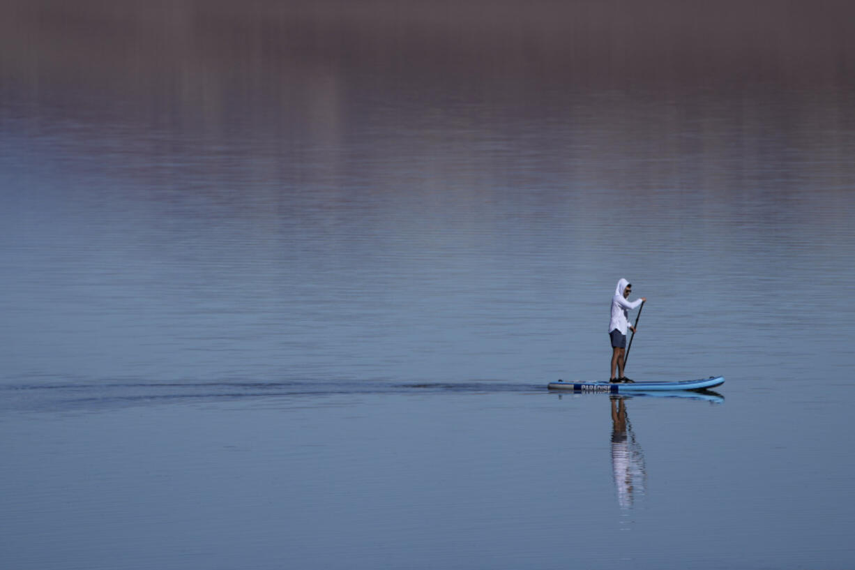 A paddle boarder paddles through water at Badwater Basin, Thursday, Feb. 22, 2024, in Death Valley National Park, Calif. The basin, normally a salt flat, has filled from rain over the past few months.
