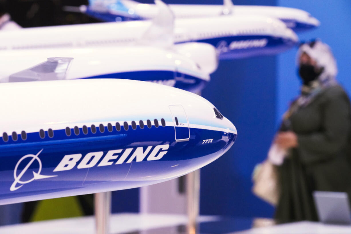FILE - A woman walks by models of Boeing Co. aircraft, including the manufacturer&rsquo;s new Boeing 777X, at the Dubai Air Show in Dubai, United Arab Emirates, Wednesday, Nov. 17, 2021. Boeing reports their earnings on Wednesday, Jan. 31, 2024.