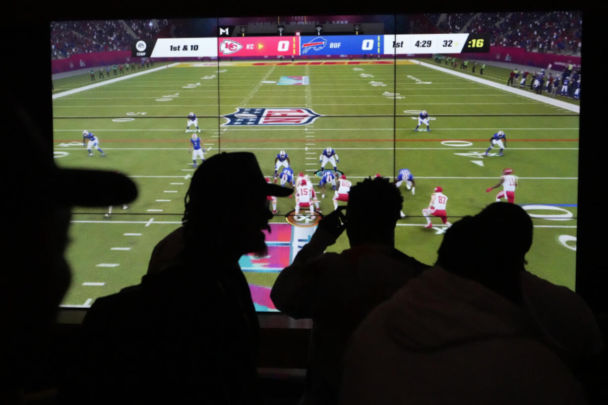 FILE - People play EA Sports&rsquo; Madden NFL video game on a projection screen at Interscope Records Studios In Santa Monica, Calif., Wednesday, June 21, 2023. Video game maker Electronic Arts is cutting about 5% of its workforce, or approximately 670 employees, Thursday, Feb. 29, 2024, as layoffs in the technology and gaming sector continue.