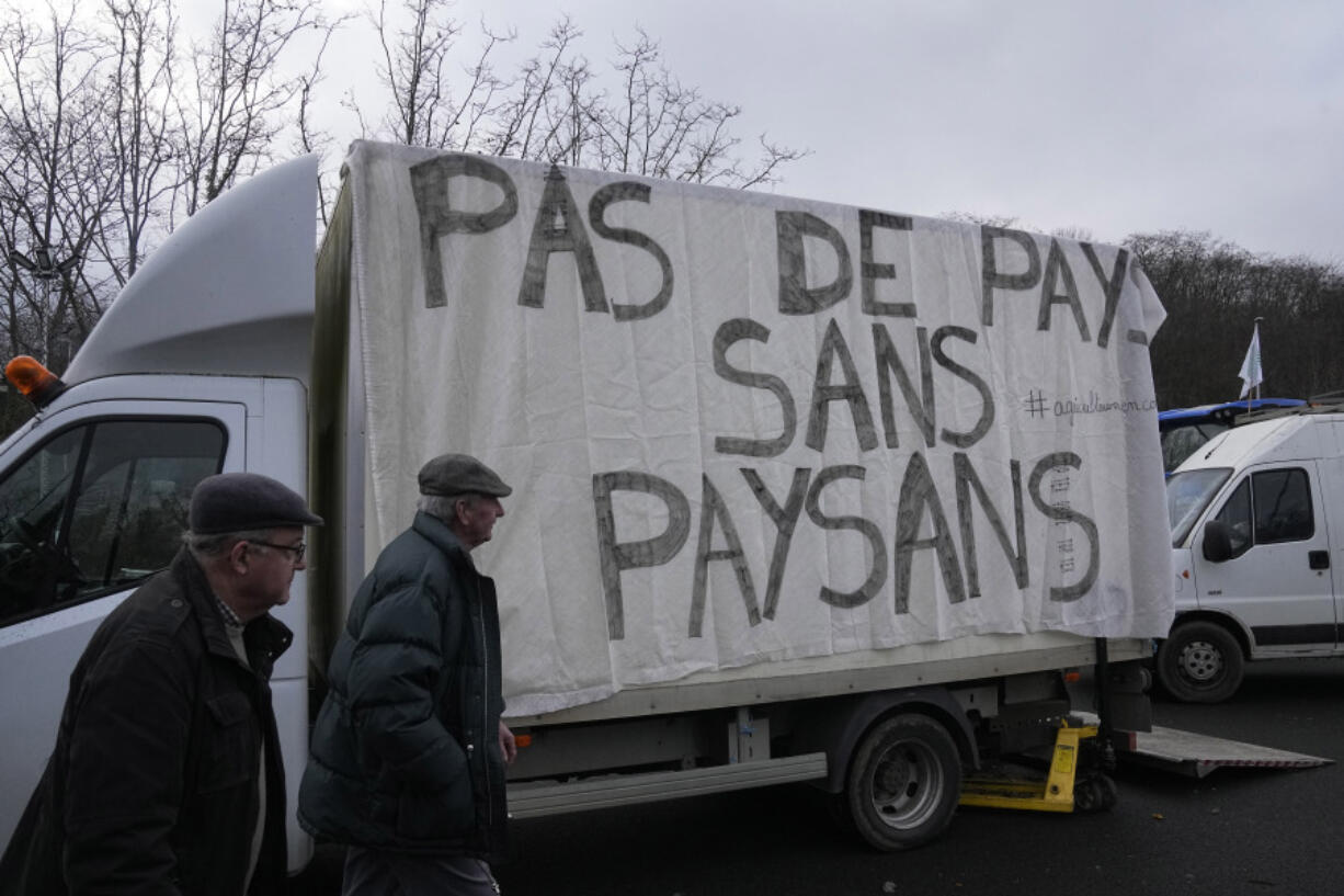 Farmers walk past a truck reading &ldquo;No country, without farmers&rdquo; on a blocked highway, Thursday, Feb.1, 2024 in Argenteuil, north of Paris. France&rsquo;s two major farmers unions announced Thursday their decision to suspend protests and lift road blockades across the country, in a dramatic development shortly after the French prime minister unveiled a new set of measures they see as &ldquo;tangible progress.&rdquo; Farmers have been protesting for days across the country to denounce low wages, heavy regulation and unfair competition from abroad.