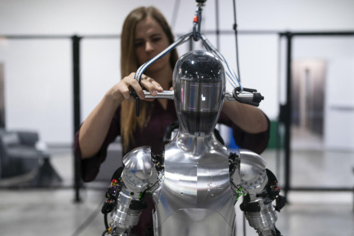 FILE -  AI engineer Jenna Reher works on humanoid robot Figure 01 at Figure AI&rsquo;s test facility in Sunnyvale, Calif., Oct. 3, 2023. ChatGPT-maker OpenAI is looking to fuse its artificial intelligence systems into the bodies of humanoid robots as part of a new deal with robotics startup Figure.  Sunnyvale, California-based Figure announced the partnership Thursday, Feb. 29, 2024, along with $675 million in venture capital funding from a group that includes Amazon founder Jeff Bezos as well as Microsoft, chipmaker Nvidia and the startup-funding divisions of Amazon, Intel and OpenAI.  (AP Photo/Jae C.