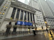 Pedestrians pass the New York Stock Exchange as snow falls on Tuesday, Feb. 13, 2024 in New York.
