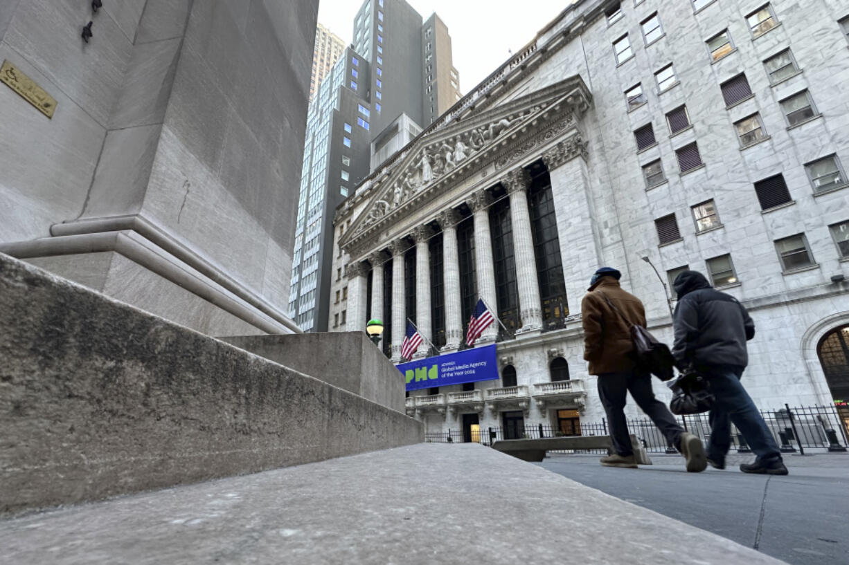 Pedestrians pass the New York Stock Exchange, rear, on Tuesday, Feb. 20, 2024 in New York.