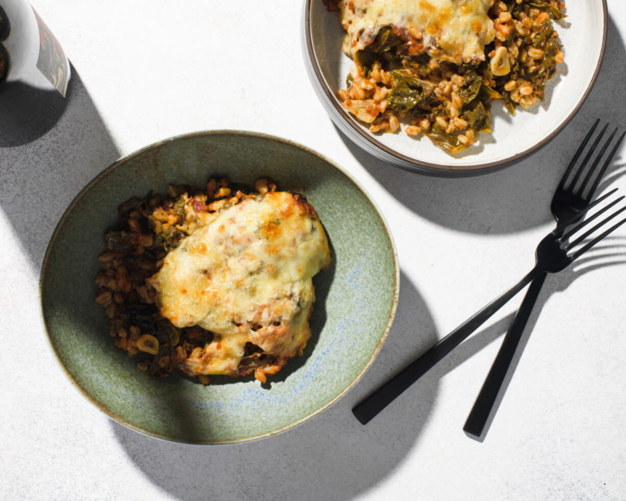 This image released by Milk Street shows a recipe for cheese baked farro with kale and tomatoes.