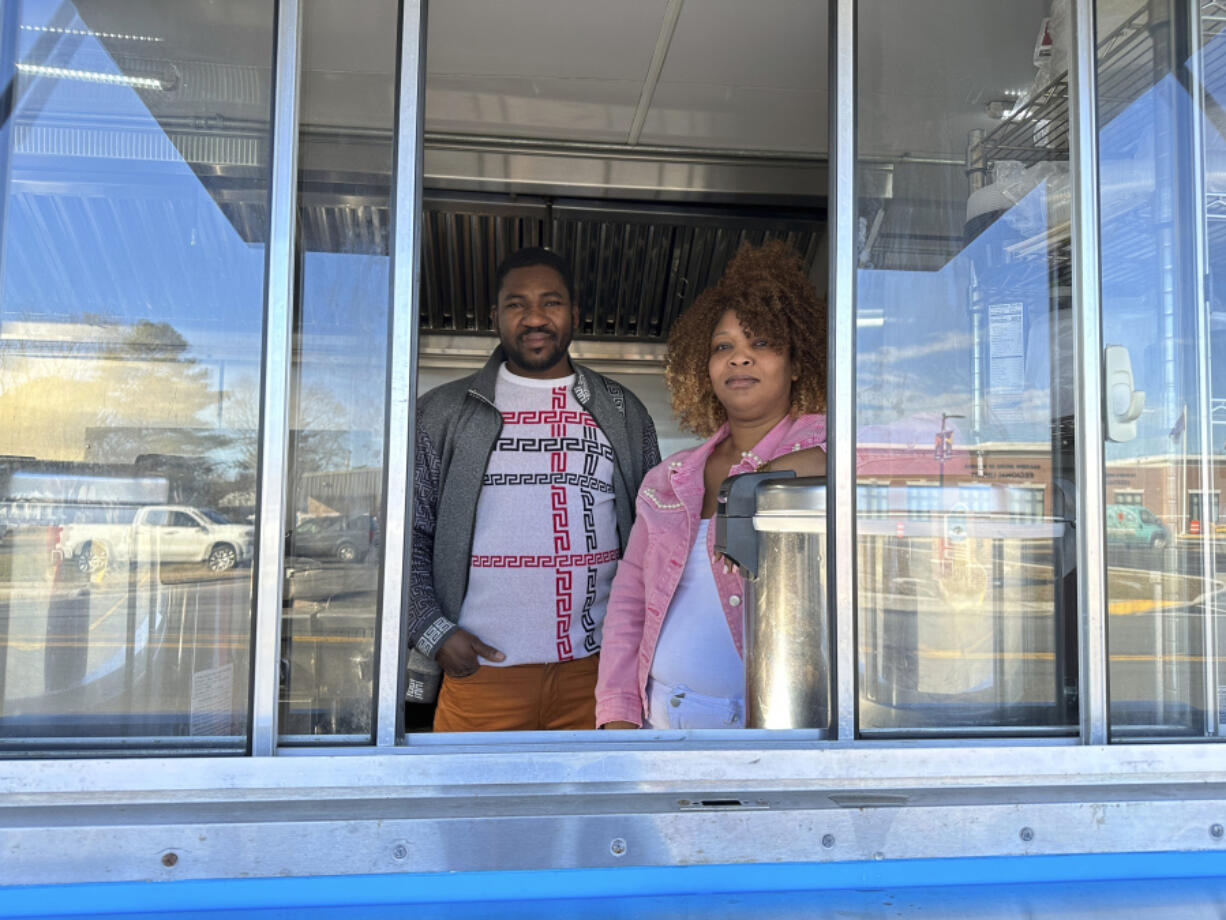 Theslet Benoir and Clemene Bastien stand at the window of their Eben-Ezer Haitian food truck in Parksley, Va., on Wednesday, Jan. 24, 2024. The married couple is suing the town in federal court over allegations that their food truck was forced to close.