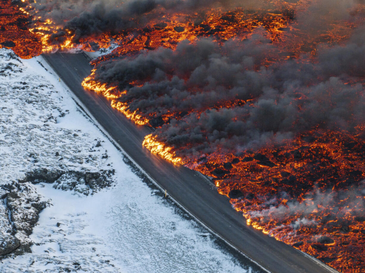 A view of lava crossing the main road to Grindav&iacute;k and flowing on the road leading to the Blue Lagoon, in Grindav&iacute;k, Iceland, Thursday, Feb. 8, 2024. A volcano in southwestern Iceland has erupted for the third time since December and sent jets of lava into the sky. The eruption on Thursday morning triggered the evacuation the Blue Lagoon spa which is one of the island nation&rsquo;s biggest tourist attractions.