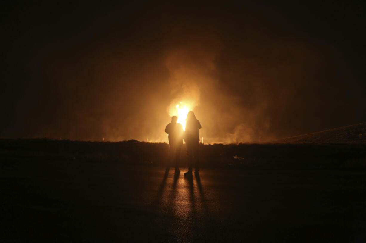 Two men look at flames after a natural gas pipeline explodes outside the city of Boroujen in the western Chaharmahal and Bakhtiari province, Iran, in early Wednesday, Feb. 14, 2024. Explosions struck a natural gas pipeline in Iran early Wednesday, with an official blaming the blasts on a &ldquo;sabotage and terrorist action&rdquo; in the country as tensions remain high in the Middle East amid Israel&rsquo;s war on Hamas in the Gaza Strip.