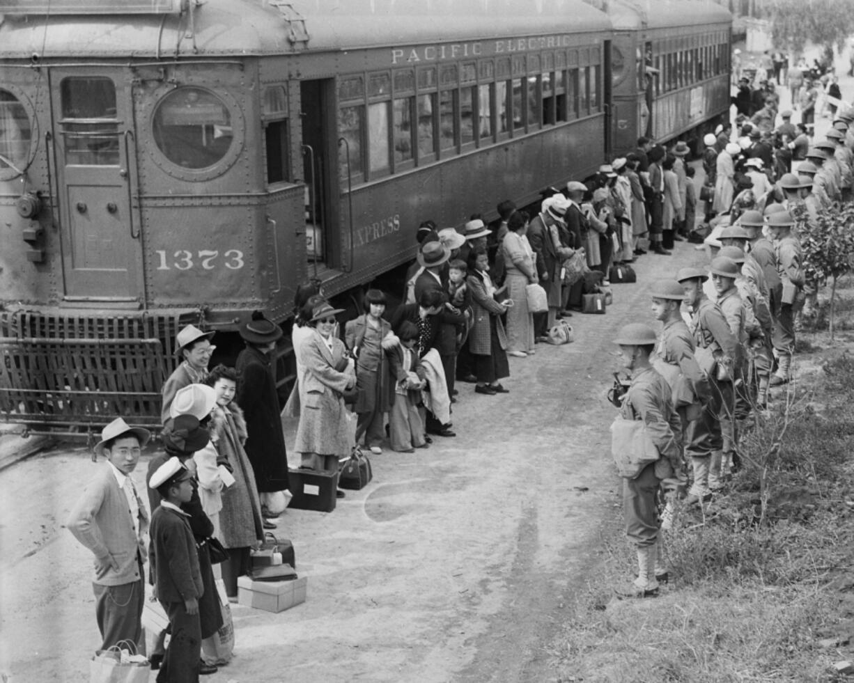 In this photo provided by the National Archives, Japanese Americans from San Pedro, Calif., arrive at the Santa Anita Assembly Center in Arcadia, Calif., on April 5, 1942. People were temporarily housed at this center at the Santa Anita race track before being moved inland to internment camps during World War II.