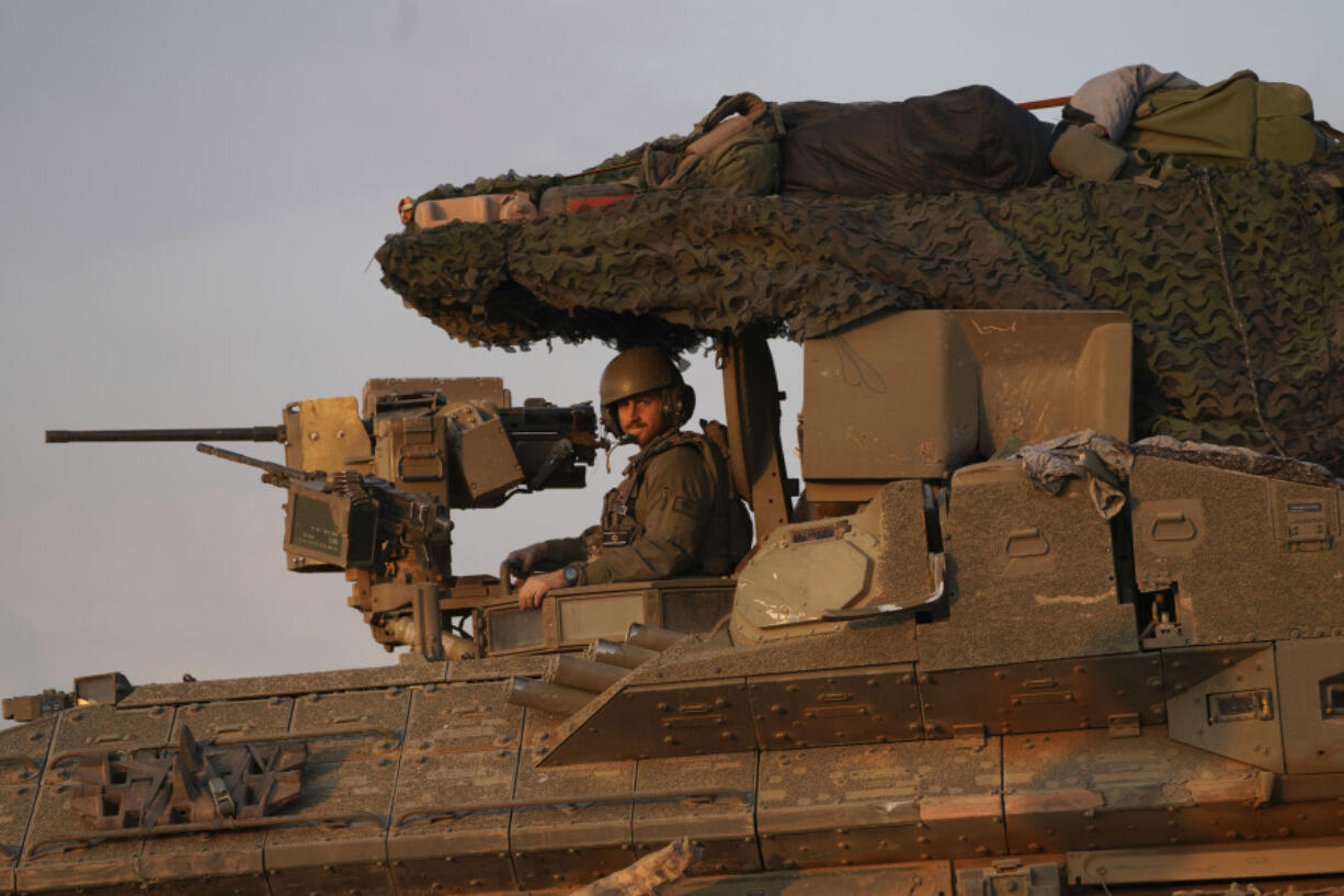 An Israeli soldier smiles from the turret of his armored vehicle in southern Israel near the Gaza border, Friday, Feb. 16, 2024.