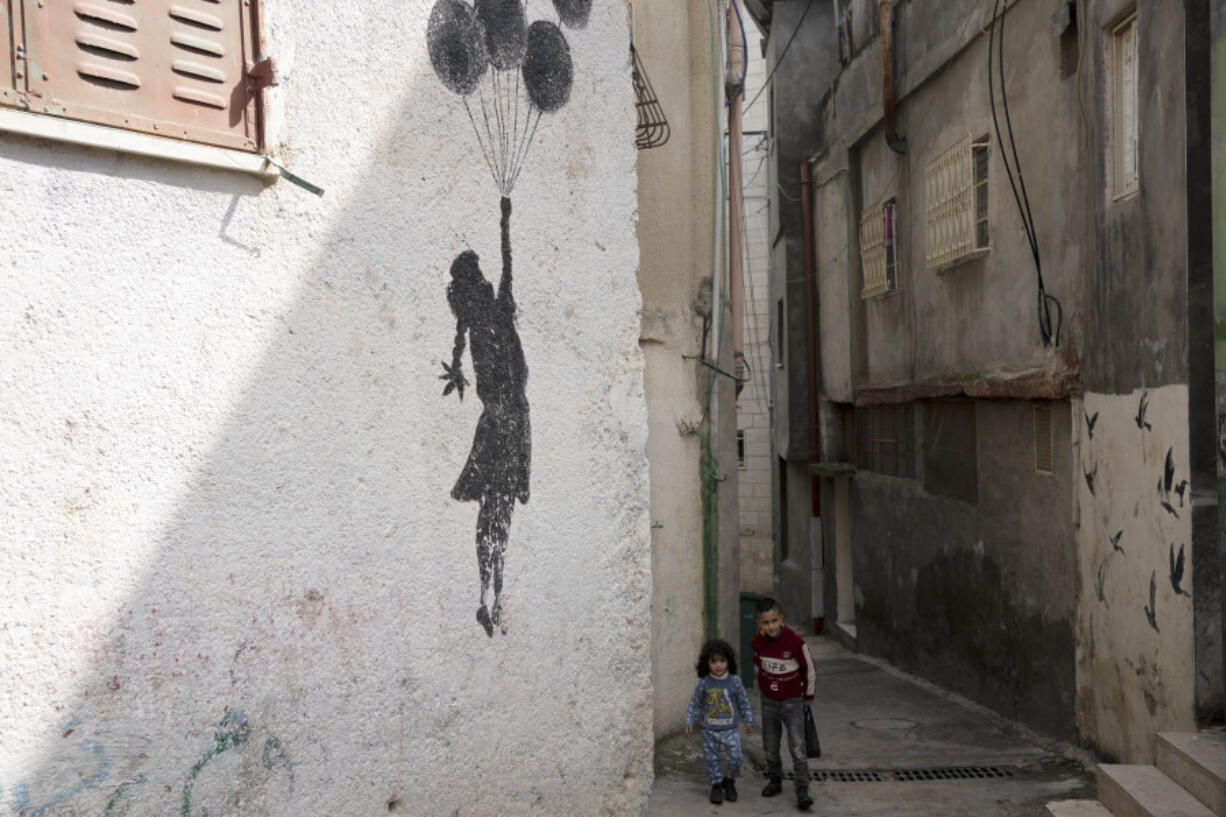 Palestinian children walk in an alley of the Aida Refugee Camp, near the health clinic and school run by the the United Nations Relief and Works Agency for Palestinian Refugees in the Near East (UNRWA) in the West Bank city of Bethlehem, Tuesday, Feb. 20, 2024.