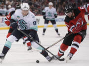 New Jersey Devils&#039; John Marino, right, gets the puck away from Seattle Kraken&#039;s Andre Burakovsky during the third period of an NHL hockey game in Newark, N.J., Monday, Feb. 12, 2024.