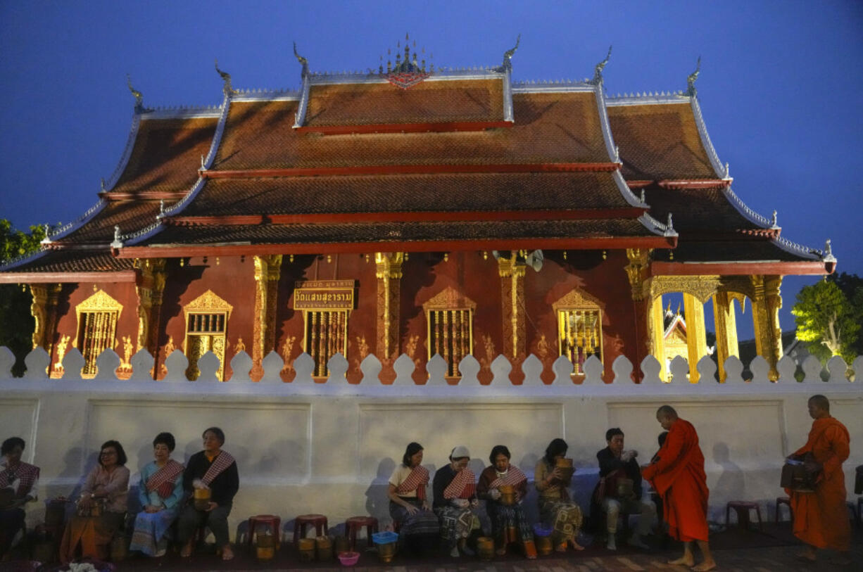 People offer food to Buddhist monks outside Sensoukharam temple in Luang Prabang, Laos, Sunday, Jan. 28, 2024.