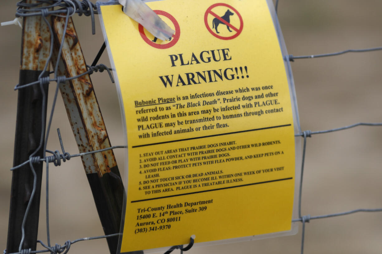 FILE - A bubonic plague warning sign is displayed at a parking lot near the Rocky Mountain Arsenal Wildlife Refuge, Saturday, Aug. 10, 2019, in Commerce City, Colo. Officials in central Oregon this week reported a case of bubonic plague in a resident who likely got the disease from a sick pet cat.