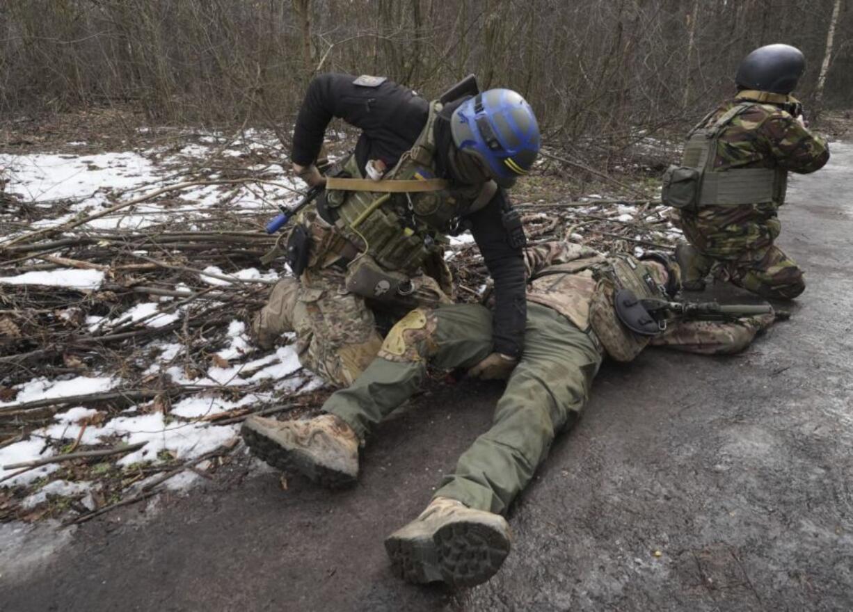 Ukrainian National guard soldiers simulate the evacuation of a wounded comrade and provide first medical help during tactical training at a shooting range in Kharkiv region, Ukraine, on Thursday, Feb. 29, 2024.