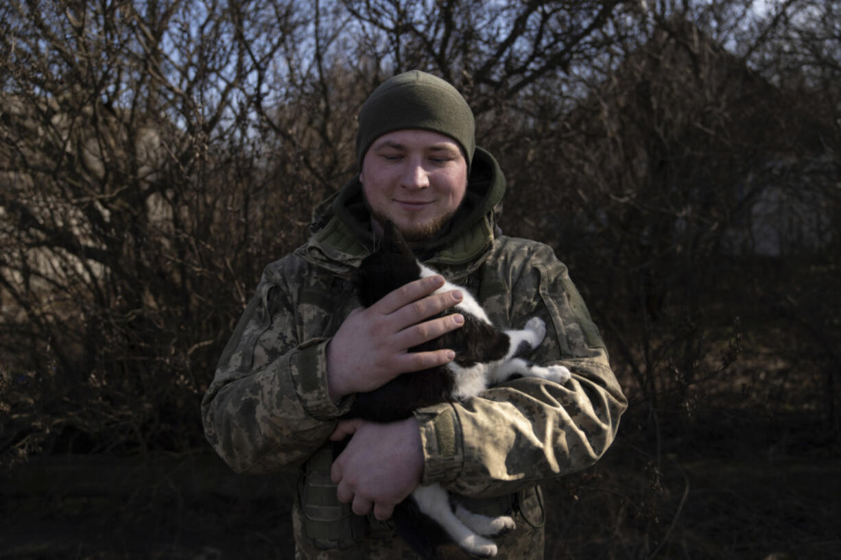 Andrii, 25, a Ukrainian commander of Grad crew, pets a cat, while waiting for orders from command centre at the frontline in Donetsk region, Ukraine, on Friday, Feb. 23, 2024.