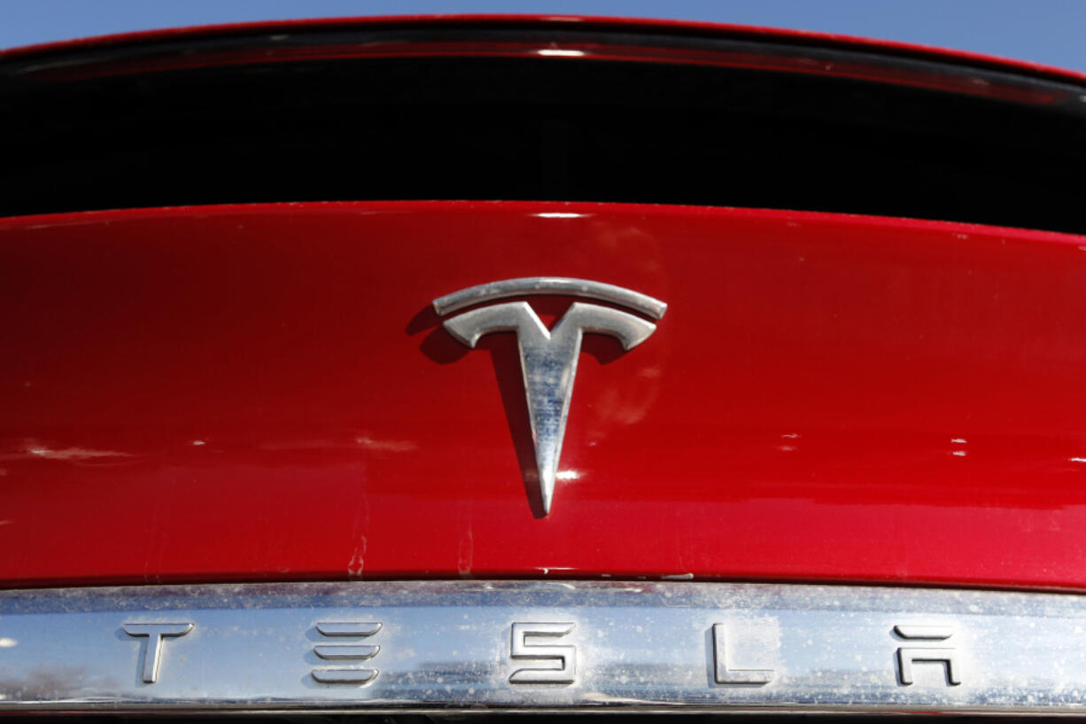 FILE - In this Feb. 2, 2020, file photo, the Tesla company logo is shown in Littleton, Colo. Tesla is recalling nearly all of the vehicles it has sold in the U.S. because some warning lights on the instrument panel are too small.