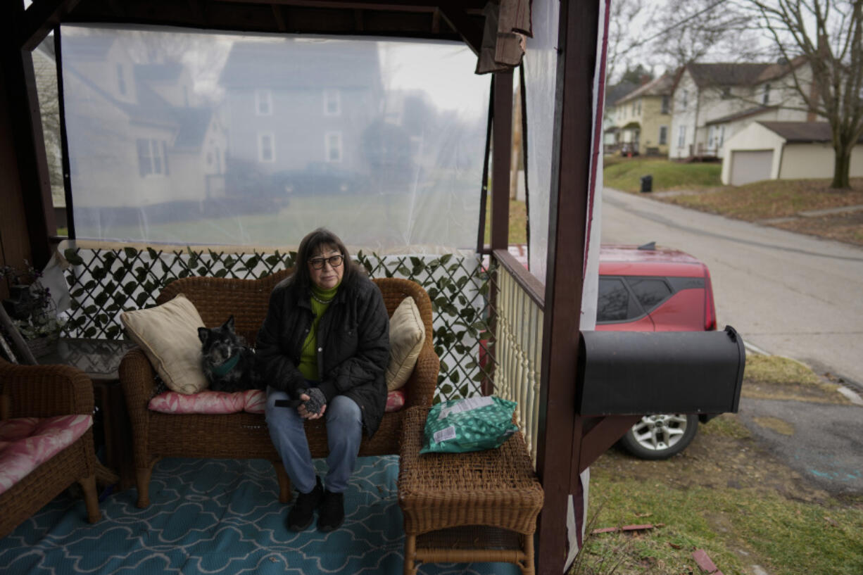 Marina Davis sits on her front porch with her dog Hunter in East Palestine, Ohio, on Tuesday, Jan. 30, 2024. Davis did not evacuate after the derailment and lives just outside the one-mile evacuation zone. Daily life largely returned to normal for residents of East Palestine, Ohio, months after a Norfolk Southern train derailed and spilled a cocktail of hazardous chemicals that caught fire a year ago, but the worries and fears are always there.