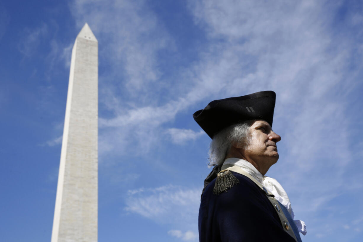 FILE - John Lopes, playing the part of President George Washington, stands near the Washington Monument following a ribbon-cutting ceremony with first lady Melania Trump to re-open the monument, Thursday, Sept. 19, 2019, in Washington. Like the other Founding Fathers, George Washington was uneasy about the idea of publicly celebrating his life. He was the first leader of a new republic &mdash; not a tyrant.