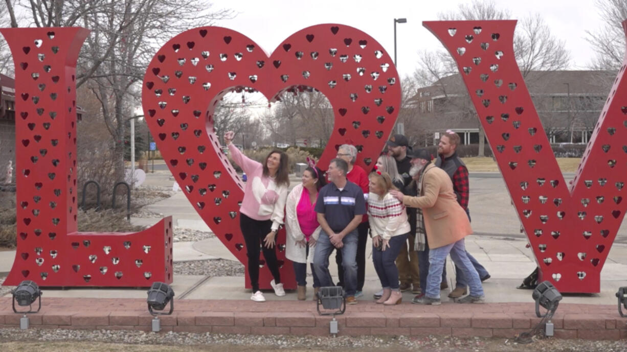 Volunteers pose for a photo in front of a &ldquo;Love&rdquo; art installation at the visitors center in Loveland, Colo., on Wednesday, Feb. 7, 2024. Every year, tens of thousands of people from around the world route their Valentine&rsquo;s Day cards to the &ldquo;Sweetheart City&rdquo; to get a special inscription and the coveted Loveland postmark. The re-mailing tradition has been going on for nearly 80 years and is the largest of its kind in the world.