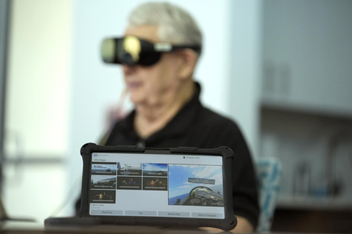 A screen displays a visual of being in a Navy fighter jet as retired Army Col. Farrell Patrick, 91, wears a Mynd Immersive virtual reality headset at John Knox Village, Wednesday, Jan. 31, 2024, in Pompano Beach, Fla. John Knox Village was one of 17 senior communities around the country that participated in a recently published Stanford University study that found that large majorities of 245 participants between 65- and 103-years-old enjoyed virtual reality, improving both their emotions and their interactions with staff.