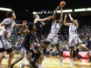 Oregon guard Jermaine Couisnard (5) and Washington forward Moses Wood (13) reach for a rebound during the second half of an NCAA college basketball game in Eugene, Ore., Thursday, Feb. 8, 2024.