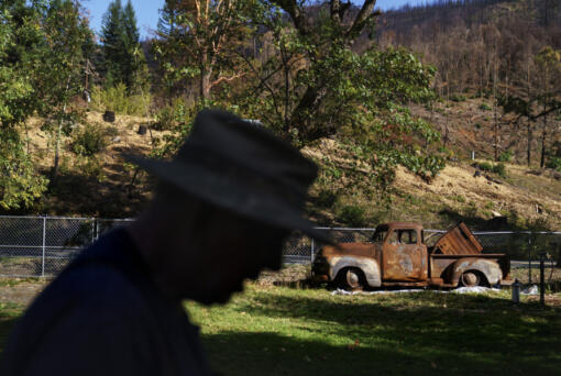 FILE - John Bain, a member of the Karuk tribe, walks by his 1954 Chevy five-window pickup that was destroyed in the Slater Fire, which tore through his property and the Klamath National Forest in Happy Camp, Calif., Oct. 6, 2021. The U.S. government has threatened to sue a unit of Warren Buffett&rsquo;s Berkshire Hathaway to recover nearly $1 billion of costs related to the wildfires in 2020 in southern Oregon and northern California. The potential lawsuits were disclosed in an annual report filed by PacifiCorp&rsquo;s parent company, Berkshire Hathaway Energy on Monday, Feb 26, 2024.