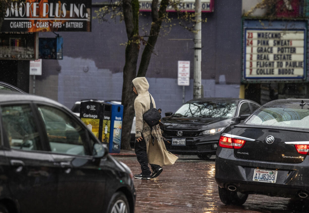 A pedestrian walks through moving traffic in downtown Seattle on Wednesday, Feb. 28, 2024.