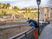 A solo traveler takes a photo of Castillo San Servando castle in Toledo, Spain.