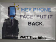 A sign is shown over a phone holder Feb. 23 in a classroom at Delta High School in Delta, Utah. At the rural Utah school, there is a strict policy requiring students to check their phones at the door when entering every class. Each classroom has a cellphone storage unit that looks like an over-the-door shoe bag with three dozen smartphone-sized slots.