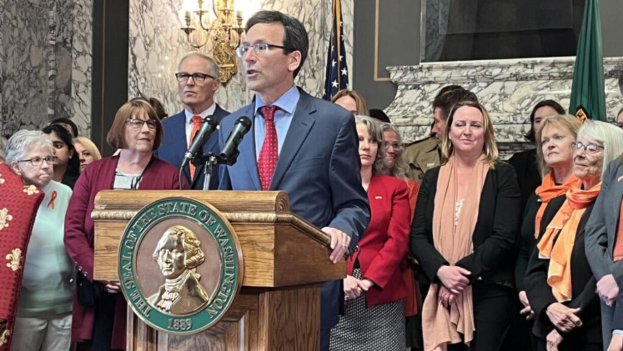 Washington state Attorney General Bob Ferguson (at podium) makes remarks prior to Gov. Jay Inslee (to the left of Ferguson) signing a package of gun legislation in April 2023. The legislation included a ban on the sale of firearms classified as assault weapons.
