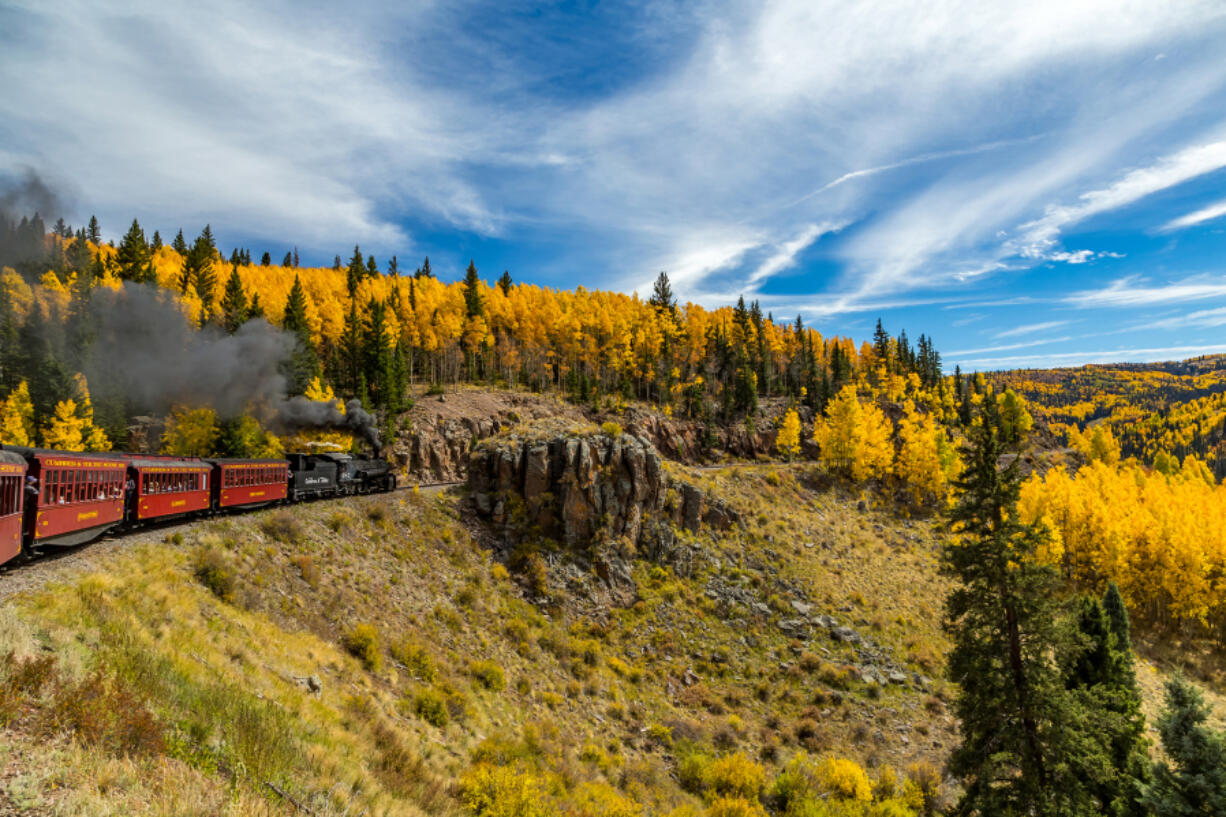 A Cumbres &amp; Toltec steam locomotive heads up a mountain with a passenger train while traveling through the San Juan National Forest on a trip from Chama, N.M., through a beautiful scenic route ending in Antonito, Colo.
