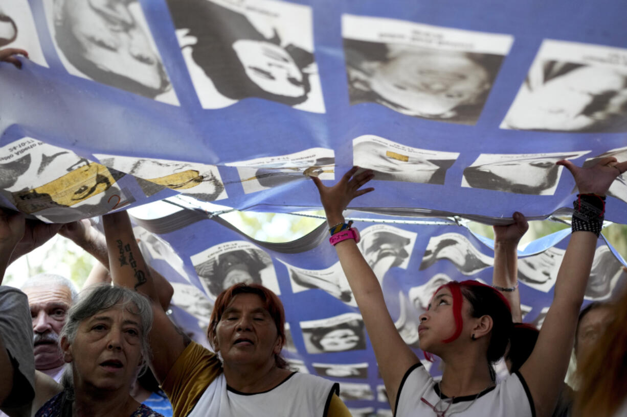 Demonstrators carry a banner with photos of people who disappeared during the 1976-1983 military dictatorship during a march March 24 commemorating the 48th anniversary of the coup in Buenos Aires, Argentina.