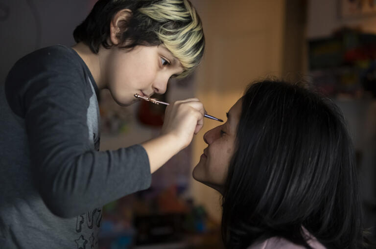 Aries Tabor, 9, of Vancouver applies makeup to his mother's face during a makeover in the front room of their home Feb. 15.