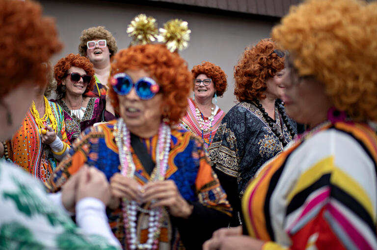An assortment of smiles, colorful caftans and vibrant wigs are seen outside Happy Family Restaurant in Battle Ground as participants in the Mrs. Roper Pub Crawl gather outside on Saturday evening, March 23, 2024. The restaurant was one of six locations in the downtown area that hosted the pub crawl.