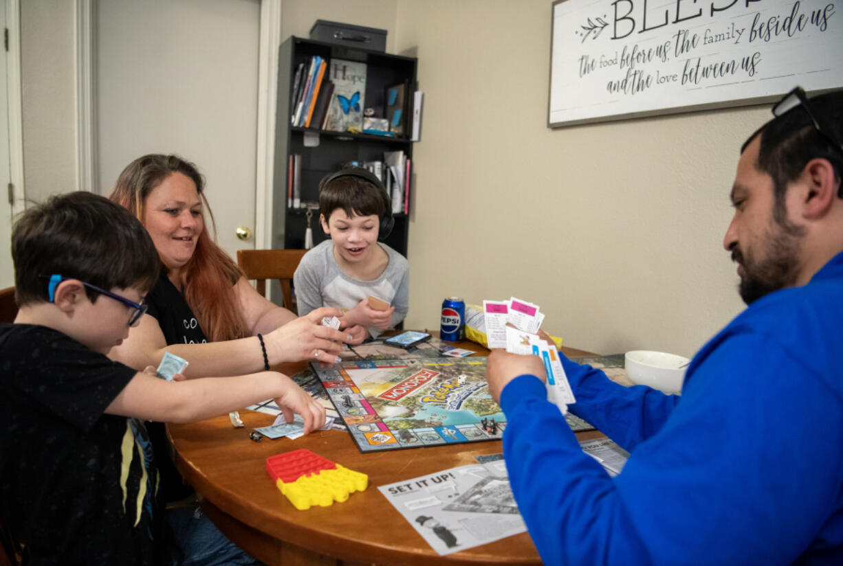 P.J. Leonard-Loera, 7, his mom Patricia Leonard, Anthony Leonard-Loera, 6, and dad Paul Loera play Pokemon Monopoly at Open House Ministries. Paul and Patricia are the first graduates from the downtown Vancouver Safe Stay shelter that opened in November 2023.