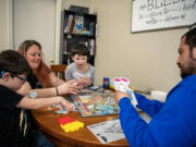 P.J. Leonard-Loera, 7, his mom Patricia Leonard, Anthony Leonard-Loera, 6, and dad Paul Loera play Pokemon Monopoly at Open House Ministries. Paul and Patricia are the first graduates from the downtown Vancouver Safe Stay shelter that opened in November 2023.