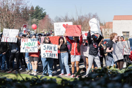 Fort Vancouver High School students wave signs and chant outside Vancouver Public Schools headquarters on Tuesday during a walk-out to protest the district&rsquo;s cuts to 262 staff positions next year.