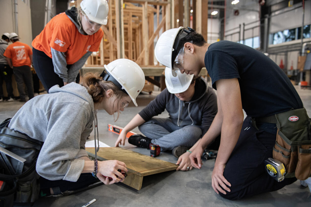 Evergreen High School sophomore Rue Rollins, 16, from left, helps build a ramp Thursday morning under the helpful eye on Trillium Allison of The Home Depot while joined by classmates Domonick Good, 15, and Juan Abundiz Piz, 14. The volunteers helped students with their building skills in hopes of encouraging them to pursue trade careers.