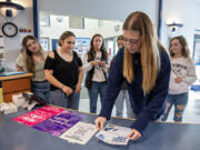 Hockinson High School students including Audrey Davis, 18, foreground right, distribute posters in the school's front office to advertise a fundraiser for period products for middle school students. The group hopes adding period products for younger girls will decrease anxiety for those who may not have access to them at home.