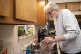 Jp Walmer washes dishes at his house in Vancouver. Walmer, 71, recently moved into housing after being homeless since August.