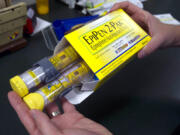FILE - In this July 8, 2016, file photo, a pharmacist holds a package of EpiPen epinephrine auto-injectors, a Mylan product, in Sacramento, Calif. Mylan N.V. reports financial results on Wednesday, Feb. 28, 2018.