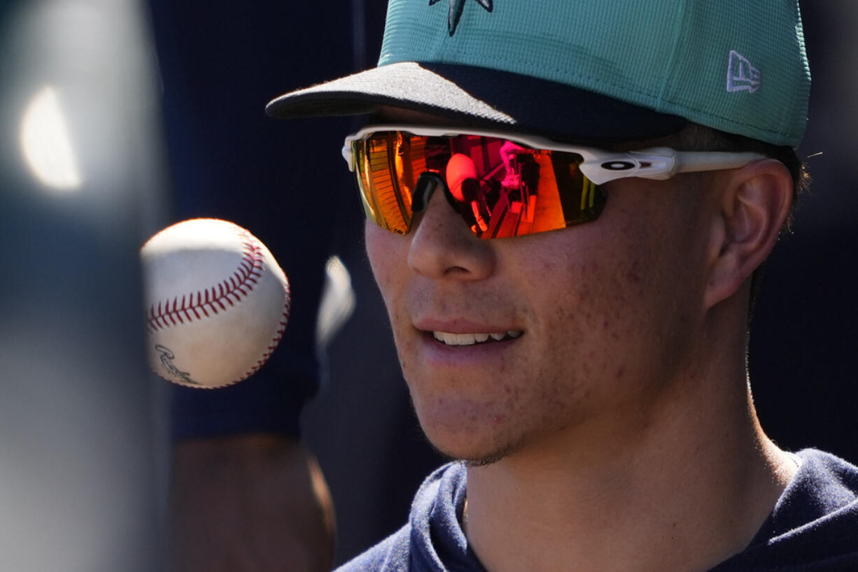 Seattle Mariners pitcher Bryan Woo tosses a ball in the dugout during a spring training baseball game against the Oakland Athletics, Saturday, March 2, 2024, in Peoria, Ariz.