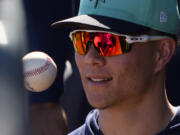 Seattle Mariners pitcher Bryan Woo tosses a ball in the dugout during a spring training baseball game against the Oakland Athletics, Saturday, March 2, 2024, in Peoria, Ariz.